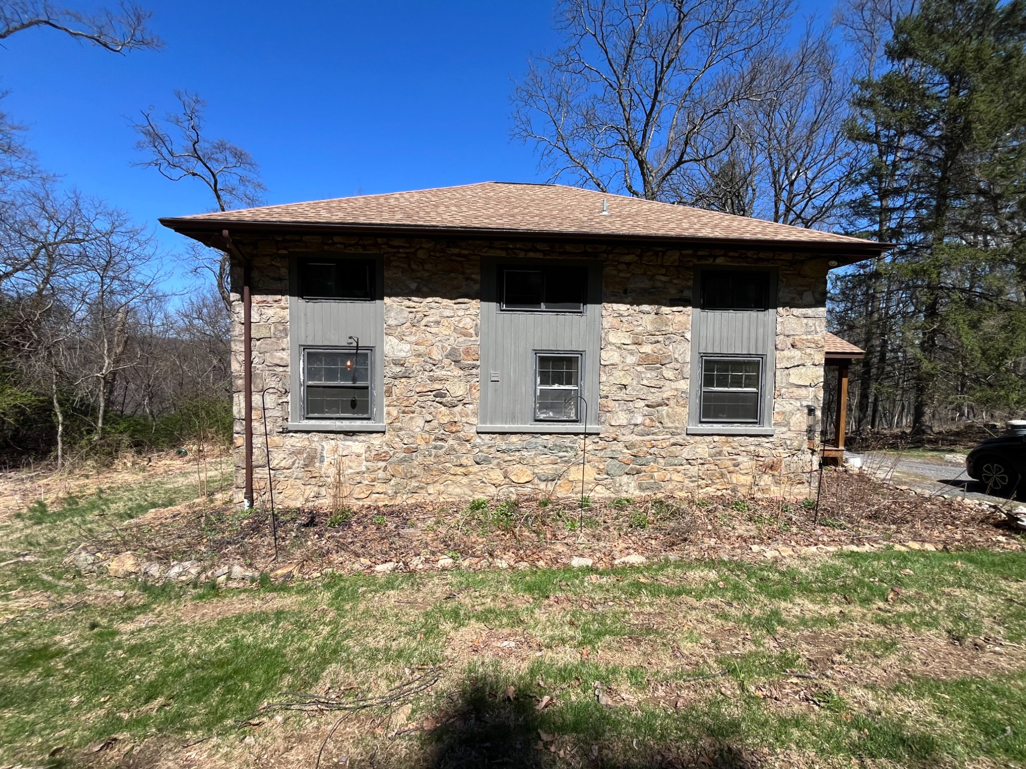 1901 stone schoolhouse with bare beds and cleared ground — before restoration
